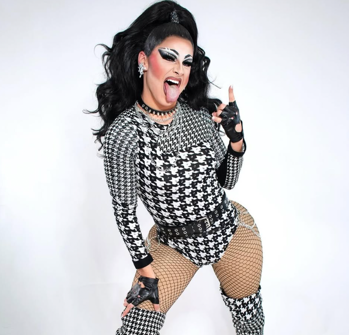 Person wearing a black and white houndstooth outfit with fishnet stockings on a white background