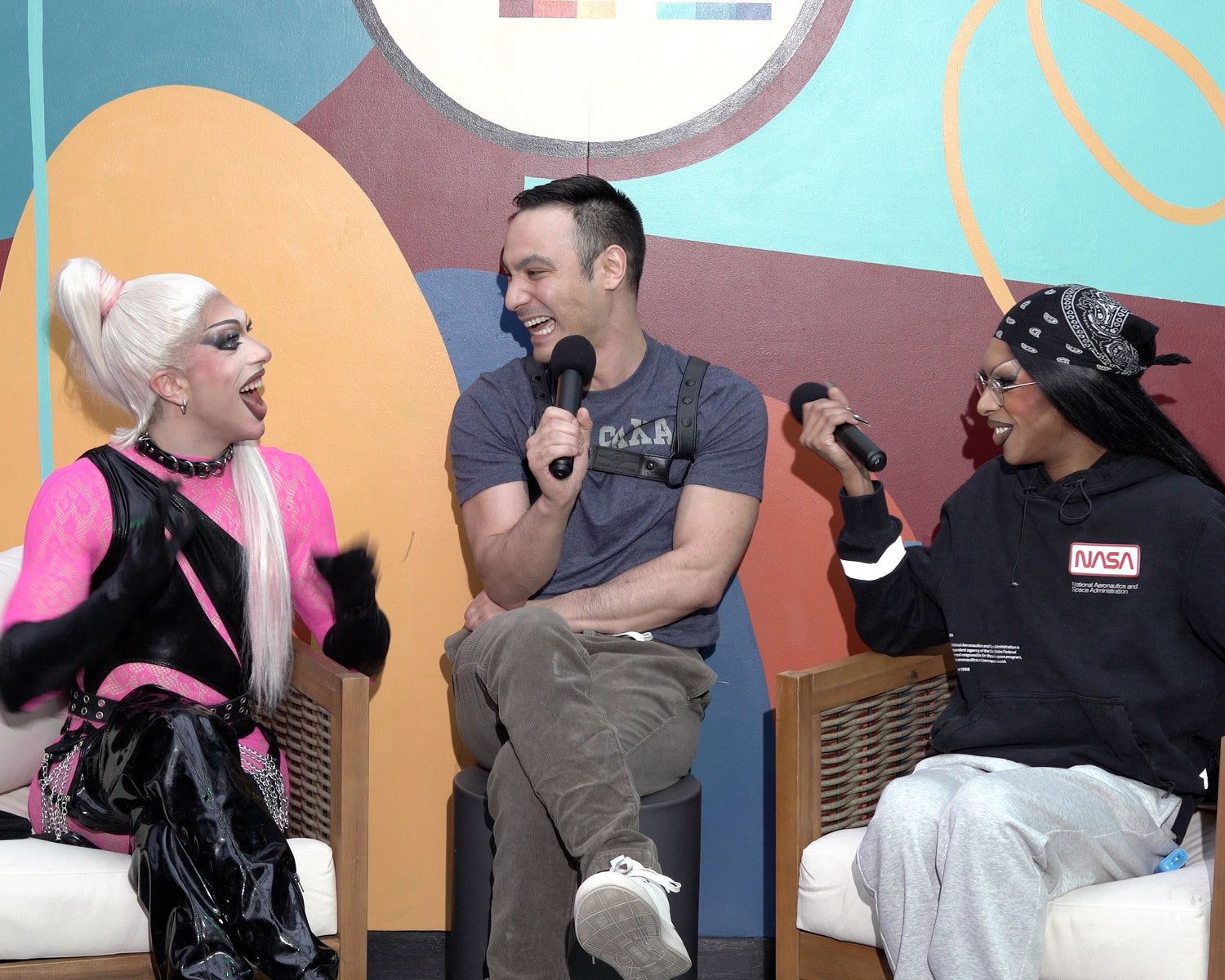 Three people on a stage with colorful abstract designs in the background